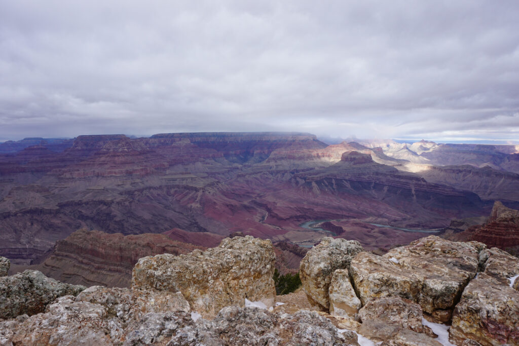 View of the Grand Canyon with a blanket of clouds and a spotlight of sunshine on the rocks in the distance